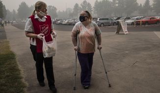 Mary Thomson, left, from Phoenix gets assistance from Salvation Army officer Tawnya Stumpf at the evacuation center set up at the Jackson County Fairgrounds on Saturday, Sept. 12, 2020 in Central Point, Ore. They lost their home to the destructive wildfires devastating the region. (AP Photo/Paula Bronstein)