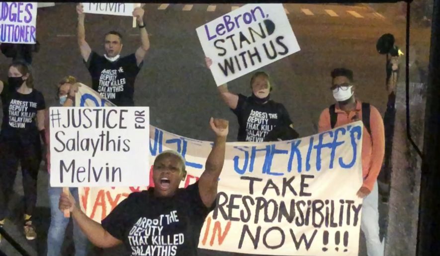 A small number of protesters of the August shooting in Central Florida of a Black man, Salaythis Melvin, hold signs and shout into megaphones, briefly blocking a bus chartered by the NBA from entering the Walt Disney World campus in Lake Buena Vista, Fla., Saturday night, Sept. 12, 2020, with the group saying it wanted LeBron James, Russell Westbrook and other top players to take notice. (AP Photo/Tim Reynolds)