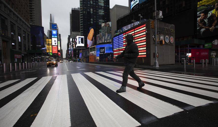 FILE - In this March 23, 2020, file photo, a man crosses the street in a nearly empty Times Square, which is usually very crowded on a weekday morning in New York. (AP Photo/Mark Lennihan, File)