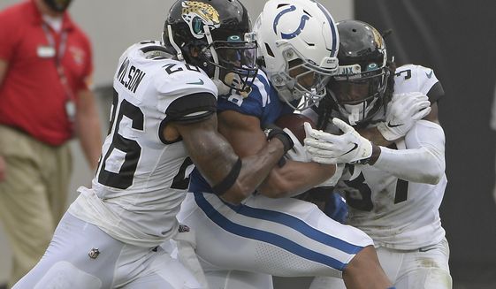 Indianapolis Colts running back Jonathan Taylor, center, is stopped by Jacksonville Jaguars safety Jarrod Wilson, left, and cornerback Tre Herndon, right, after a gain during the first half of an NFL football game, Sunday, Sept. 13, 2020, in Jacksonville, Fla. (AP Photo/Phelan M. Ebenhack)