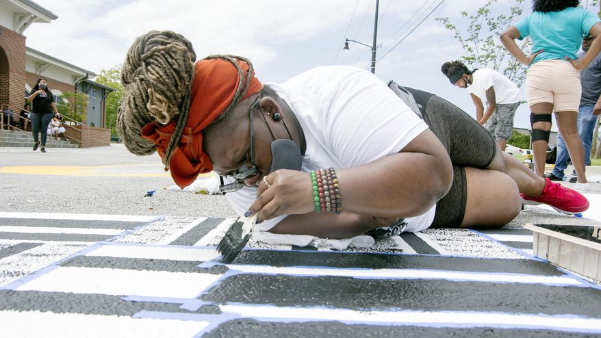 Artist Jasmine D. works on some detail work on a Black Lives Matter street mural on Barnes Street in Florence, S.C., Sunday morning, Sept. 6, 2020. (Matthew Robertson/The Morning News via AP)