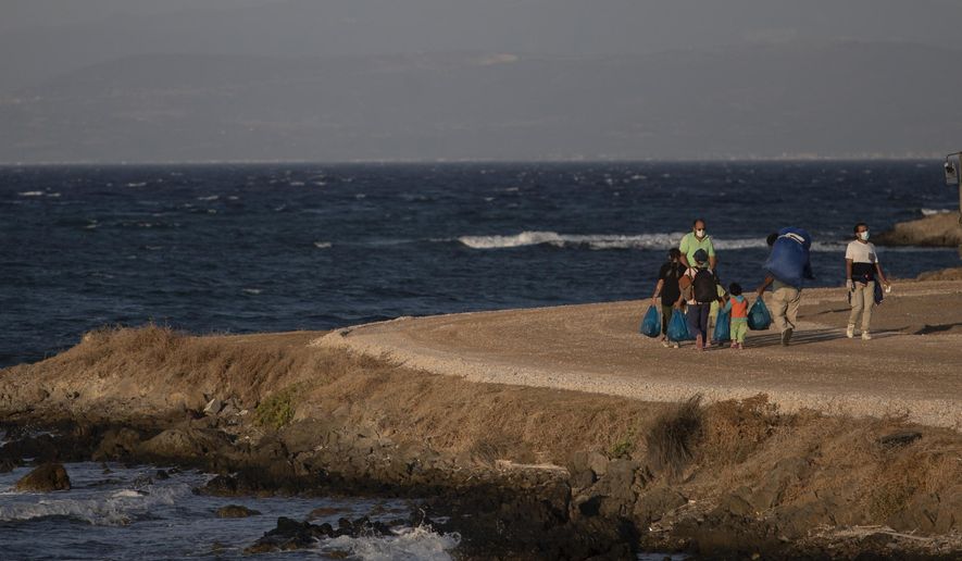 Migrants with their belongings walk near the new temporary refugee camp in Karatepe near Mytilene town, on the northeastern island of Lesbos, Greece, Monday, Sept. 14, 2020. Greece's prime minister demanded Sunday that the European Union take a greater responsibility for managing migration into the bloc, as Greek authorities promised that 12,000 migrants and asylum-seekers left homeless after fire gutted an overcrowded camp would be moved shortly to a new tent city. (AP Photo/Petros Giannakouris)