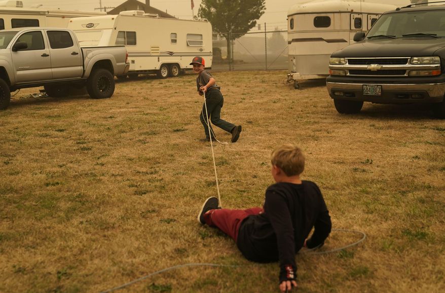 Bransen Faulhaber, 7, lassoes Kole Michael Jones at an evacuation center for the Riverside Fire at the Clackamas County Fairgrounds, Sunday, Sept. 13, 2020, in Canby, Ore. The two are staying in RVs with their families after evacuating their homes due to the fire danger. (AP Photo/John Locher)