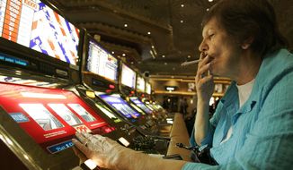 FILE - In this Dec. 28, 2005, file photo, Judy King of Daytona Beach, Fla., holds her cigarette while playing a slot machine at the MGM Grand hotel-casino in Las Vegas. One of the last Las Vegas Strip resorts to reopen after coronavirus closures will be the first to be smoke-free, MGM Resorts International announced Monday, Sept. 14, 2020. Park MGM will prohibit tobacco smoke inside when it opens Sept. 30, said Anton Nikodemus, president and chief operating officer of the 3,000-room property that many remember as the Monte Carlo casino-hotel. (AP Photo/Jae C. Hong, File)