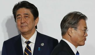 FILE - In this June 28, 2019, file photo, South Korean President Moon Jae-in, right, walks by Japanese Prime Minister Shinzo Abe upon his arrival for a welcome and family photo session at the G-20 leaders summit in Osaka, western Japan. When Abe announced his decision last month to step down as Japan’s prime minster over an illness, Moon’s office issued glowing praise about his unspecified contributions to bilateral ties. The rare praise came after years of intense diplomatic rows over wartime history, trade and military issues that sank the relationship between the key U.S. allies to post-war lows. (Kim Kyung-Hoon/Pool Photo via AP, File)