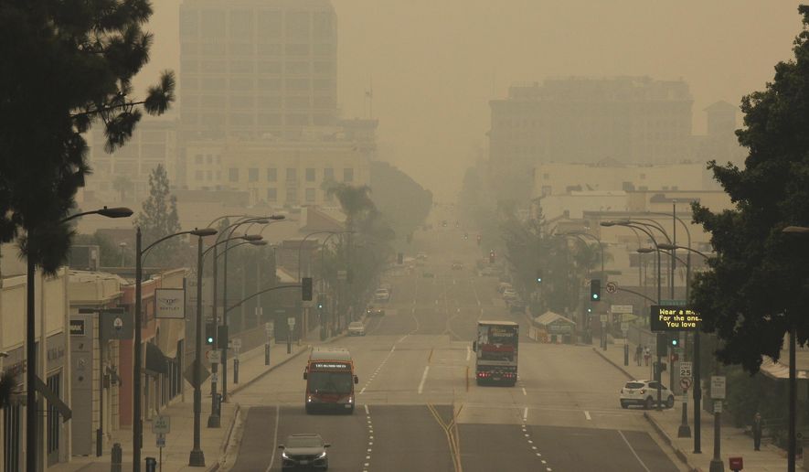 FILE - Smoke from wildfires fills the sky over Pasadena, Calif., in this view looking east down Colorado Boulevard in a Saturday, Sept. 12, 2020 file photo. The fires consuming the forests of California and Oregon and darkening the skies over San Francisco and Portland are also damaging an economy already struggling with the coronavirus outbreak. In the communities where they are raging, wildfires are destroying property, running up huge losses for property insurers and putting a strain on economic activity that could linger for a year or more.  (AP Photo/John Antczak, File)