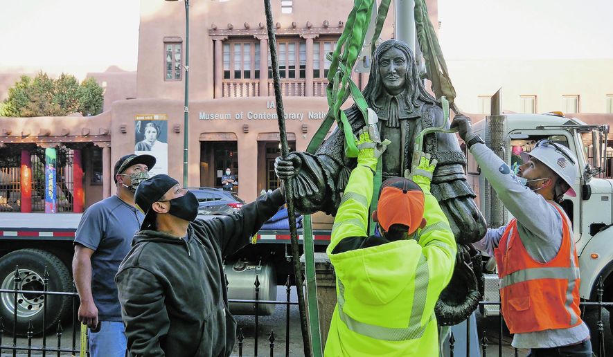 Workers fit harnesses around a statue of Don Diego de Vargas during the statue's removal from Cathedral Park in Santa Fe, N.M., Thursday, June 18, 2020. Crews in Santa Fe on Thursday removed the statue of the Spanish territorial governor from the city park and two other markers were slated to come down as monuments to historical figures were being dismantled across the country. (Matt Dahlseid/Santa Fe New Mexican via AP)