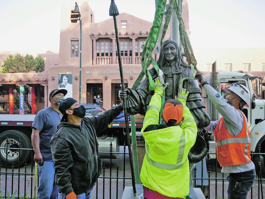Workers fit harnesses around a statue of Don Diego de Vargas during the statue's removal from Cathedral Park in Santa Fe, N.M., Thursday, June 18, 2020. Crews in Santa Fe on Thursday removed the statue of the Spanish territorial governor from the city park and two other markers were slated to come down as monuments to historical figures were being dismantled across the country. (Matt Dahlseid/Santa Fe New Mexican via AP)