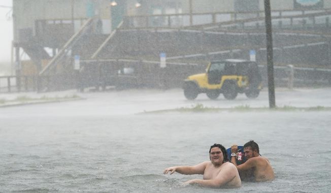 People play in a flooded parking lot at Navarre Beach, Tuesday, Sept. 15, 2020, in Pensacola Beach, Fla. Hurricane Sally is crawling toward the northern Gulf Coast at just 2 mph, a pace that&#x27;s enabling the storm to gather huge amounts of water to eventually dump on land. (AP Photo/Gerald Herbert)