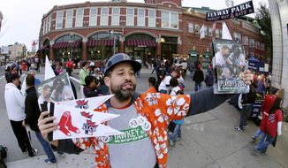 FILE - In this Oct. 19, 2013, file photo, Tim Lampa hawks programs and Boston Red Sox pennants outside Fenway Park before Game 6 of the American League baseball championship series between the Red Sox and the Detroit Tigers in Boston. Ballpark area businesses are struggling during the 2020 season while fans are not in attendance due to the COVID-19 pandemic. (AP Photo/Charlie Riedel, File)