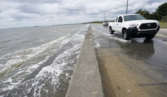 Waters from the Guld of Mexico poor onto a local road, Monday, Sept. 14, 2020, in Waveland, Miss. Hurricane Sally, one of a record-tying five storms churning simultaneously in the Atlantic, closed in on the Gulf Coast on Monday with rapidly strengthening winds of at least 100 mph (161 kph) and the potential for up to 2 feet (0.6 meters) of rain that could bring severe flooding. (AP Photo/Gerald Herbrt)