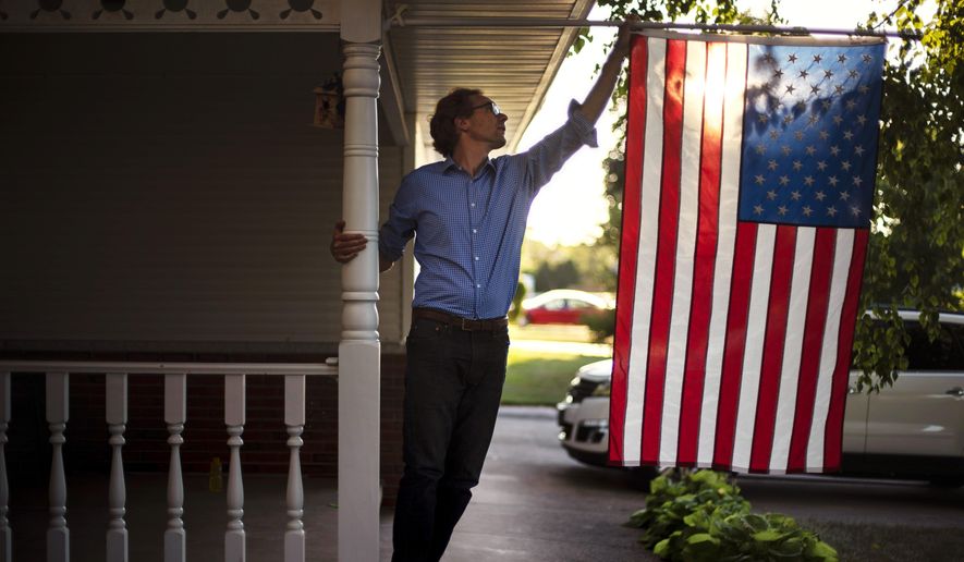 Outagamie County Executive Tom Nelson adjusts the American flag hanging off his front porch in Appleton, Wis., Aug. 18, 2020. (AP Photo/David Goldman/File)
