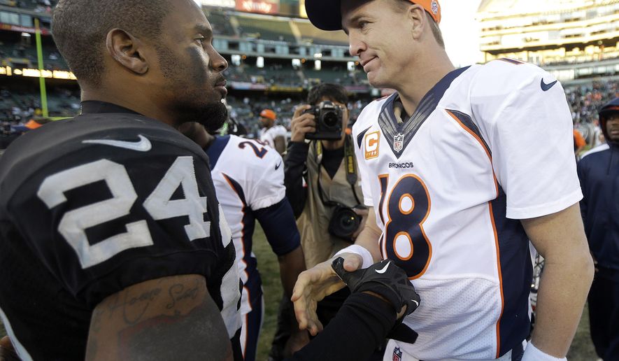 FILE - In this Dec. 29, 2013, file photo, Oakland Raiders cornerback Charles Woodson (24) talks with Denver Broncos quarterback Peyton Manning (18) after an NFL football game in Oakland, Calif. Peyton Manning and Charles Woodson are among 14 first-year eligible candidates for the Pro Football Hall of Fame. (AP Photo/Marcio Jose Sanchez, File)