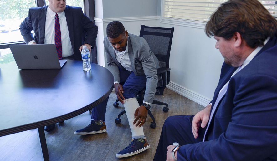 FILE - In this on Aug. 5, 2020, file photo, Jeffery Ryans points at his ankle as he discusses his encounter with Salt Lake City police at his attorney's office, in Salt Lake City. A Utah police officer was charged with aggravated assault after ordering a dog to attack Ryans who had put his hands in the air, prosecutors announced Wednesday, Sept. 16, 2020. Ryans was in his backyard on April 24 when police responded to a domestic dispute call. (Leah Hogsten/The Salt Lake Tribune via AP, Filw)
