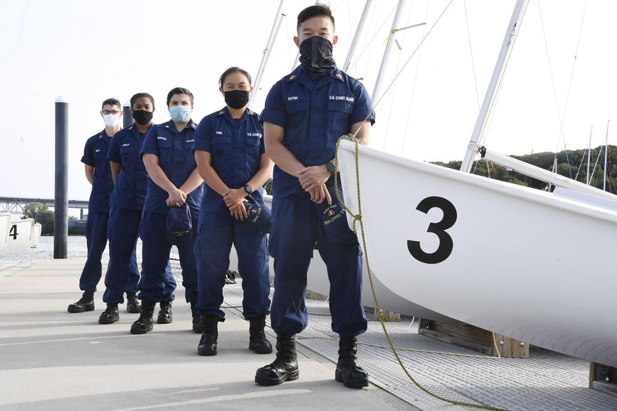 In this Monday Sept. 14, 2020 photo, From back left, Coast Guard Academy Cadets Henry Smith, Branyelle Carillo, Mia Haskovec, Jordan Park, and Tyler Huynh, pose for a photograph at the Seamanship Sailing Center at the United State Coast Guard Academy in New London, Conn. A group of Coast Guard cadets spent part of their summer filling in on a critical national security mission after a case of COVID-19 sidelined crew members on a cutter being sent to patrol the US-Russia border. (AP Photo/Jessica Hill)