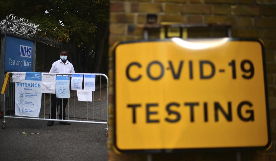 A member of staff stands at the entrance to a coronavirus testing centre in Newham, east London, Wednesday, Sept. 16, 2020. The British government plans to ration coronavirus testing, giving priority to health workers and care home staff after widespread reports that people throughout the country were unable to schedule tests. Prime Minister Boris Johnson on Wednesday will face questions about his handling of the COVID-19 pandemic in the House of Commons and before a key committee amid the outcry over the shortage of testing. (Victoria Jones/PA via AP)
