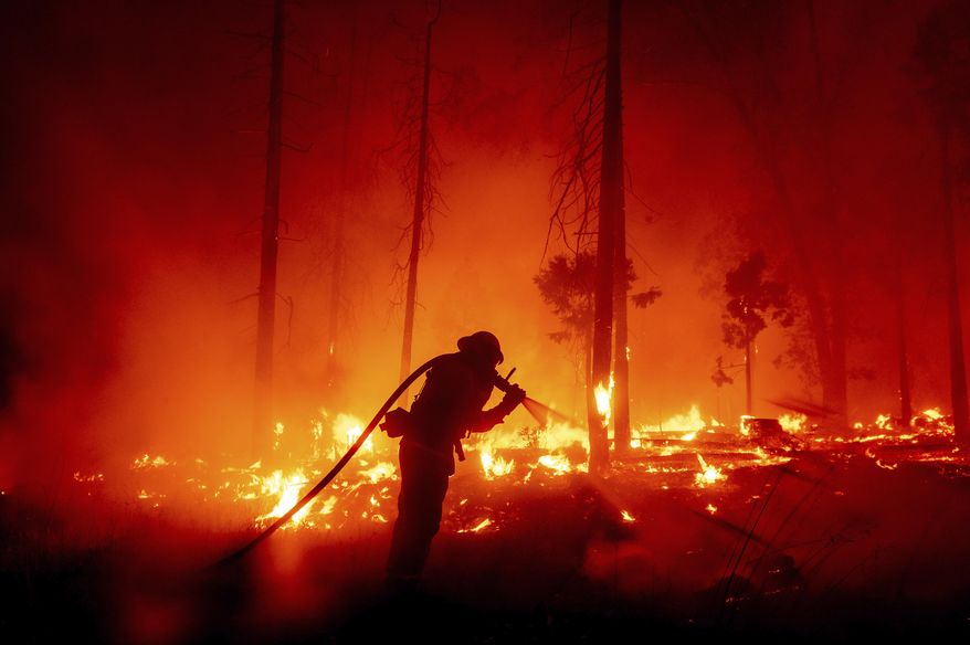 FILE - In this Sept. 7, 2020, file photo, a firefighter battles the Creek Fire as it threatens homes in the Cascadel Woods neighborhood of Madera County, Calif. This year's fires have taxed the human, mechanical and financial resources of the nation's wildfire fighting forces to a degree that few past blazes did. And half of the fire season is yet to come. (AP Photo/Noah Berger,File)