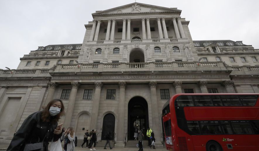 FILE - In this file photo dated Wednesday, March 11, 2020, pedestrians wearing face masks walk past the Bank of England in London.  The Bank of England kept its main interest rate unchanged at the record low of 0.1% on Thursday Sept. 17, 2020, as it waits to see how the economy recovers from recession and what Britain’s future trade relationship with the European Union will be. (AP Photo/Matt Dunham, FILE)