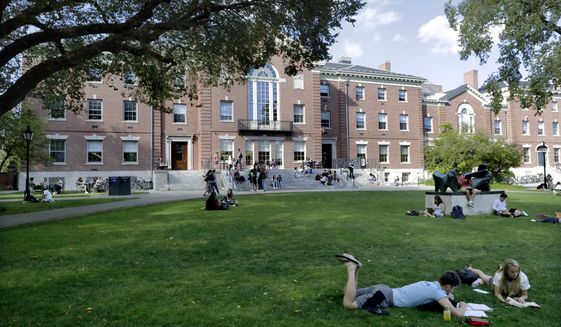 FILE - In this Sept. 25, 2019, file photo, people rest on grass while reading at Brown University in Providence, R.I. The university and attorneys for student-athletes, who challenged the Ivy League school&#39;s decision to reduce several women&#39;s varsity sports teams to club status, announced a proposed settlement Thursday, Sept. 17, 2020. (AP Photo/Steven Senne, File)