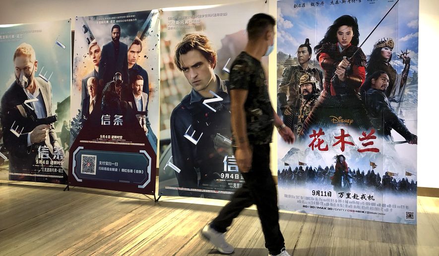 A man wearing a face mask walks past a poster for the Disney movie &amp;quot;Mulan&amp;quot; at a movie theater in Beijing, on Sept. 11, 2020. The remake of “Mulan” struck all the right chords to be a hit in the key Chinese market. Disney cast beloved actresses Liu Yifei as Mulan and removed a popular dragon sidekick in the original to cater to Chinese tastes. (AP Photo/Mark Schiefelbein)