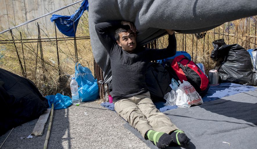 Homeless Afghan refugee Ayoub Husseini, who has lost the use of his legs after a construction accident, sits on a blanket with his belongings on the terrace of a commercial building on the island of Lesbos. Greece, Monday, Sept. 14, 2020. Ayoub who hopes to receive medical treatment for his injuries in Europe, is one of thousands of asylum-seekers left homeless after a fire gutted Moria refugee camp on the island. (AP Photo/Petros Giannakouris)