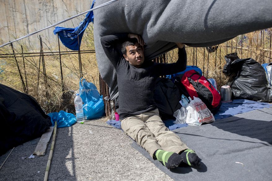 Homeless Afghan refugee Ayoub Husseini, who has lost the use of his legs after a construction accident, sits on a blanket with his belongings on the terrace of a commercial building on the island of Lesbos. Greece, Monday, Sept. 14, 2020. Ayoub who hopes to receive medical treatment for his injuries in Europe, is one of thousands of asylum-seekers left homeless after a fire gutted Moria refugee camp on the island. (AP Photo/Petros Giannakouris)
