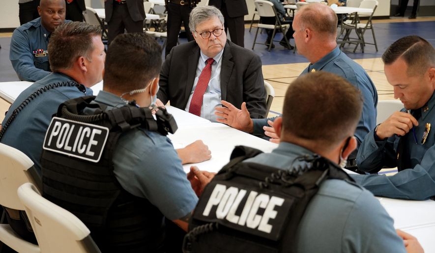 FILE - In this Aug. 19, 2020, photo Attorney General William Barr participates in a roll call with police officers from the Kansas City Police Department in Kansas City, Mo. In a private conference call this week with his U.S. attorneys nationwide, Attorney General William Barr said he wanted prosecutors to be aggressive in charging demonstrators who cause violence. (AP Photo/Mike Balsamo, File)