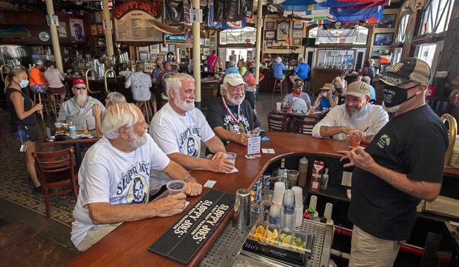 In this photo provided by the Florida Keys News Bureau, Ernest Hemingway look-alikes, including from left, Dusty Rhodes, Tim Stockwell and Charlie Boice chat with bartender Lou Gammel, right, at Sloppy Joe&#x27;s, Thursday, Sept. 17, 2020, in Key West, Fla. The iconic Florida Keys bar reopened Thursday after being sidelined by the coronavirus pandemic, with the annual Hemingway Look-Alike Contest, that was to mark its 40th anniversary and take place in July, a highlight of Key West&#x27;s Hemingway Days festival. Boice won the contest in 2015. (Rob O&#x27;Neal/Florida Keys News Bureau via AP)
