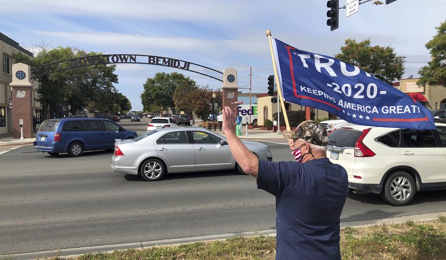 A supporter of President Donald Trump waves to passing cars Friday, Sept. 18, 2020 in Bemidji, Minn., where the President is slated to hold a campaign rally at the airport in the early evening. (AP Photo/Jim Mone)
