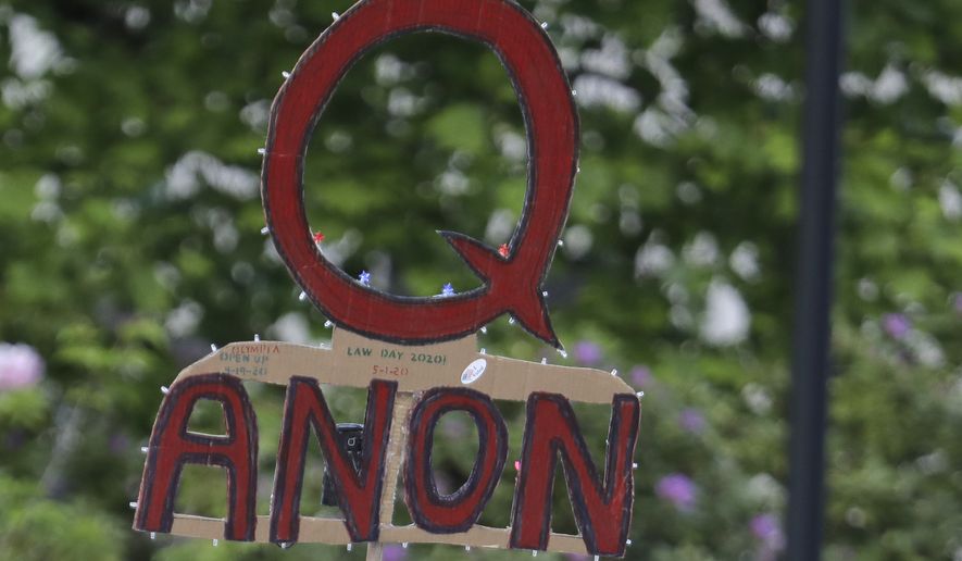 In this May 14, 2020 file photo, a person carries a sign supporting QAnon at a protest rally in Olympia, Wash. (AP Photo/Ted S. Warren, File)