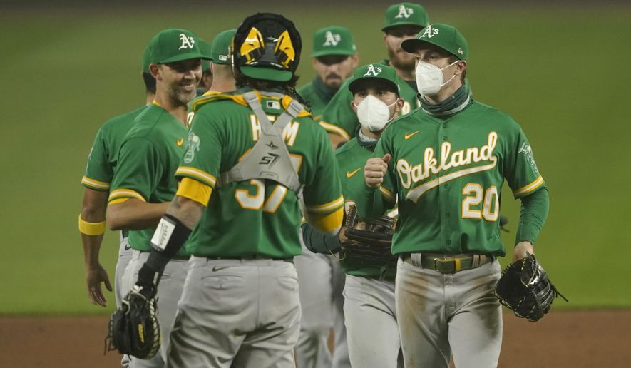 Oakland Athletics outfielders Mark Canha (20) and Ramon Laureano, second from right, wear masks as they greet teammates after they defeated the Seattle Mariners in the second baseball game of a doubleheader, Monday, Sept. 14, 2020, in Seattle. Both games were played in air smoky from wildfires in Oregon, Washington, and California. (AP Photo/Ted S. Warren)