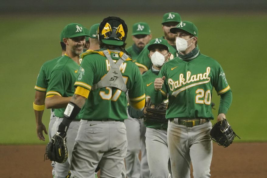 Oakland Athletics outfielders Mark Canha (20) and Ramon Laureano, second from right, wear masks as they greet teammates after they defeated the Seattle Mariners in the second baseball game of a doubleheader, Monday, Sept. 14, 2020, in Seattle. Both games were played in air smoky from wildfires in Oregon, Washington, and California. (AP Photo/Ted S. Warren)