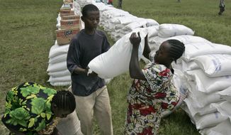 In this Nov. 14, 2008, file photo, a woman receives a bag of maize meal from the World Food Program in the town of Rutshuru, eastern Congo. The World Food Program chief warned Thursday, Sept. 17, 2020, that millions of people are closer to starvation because of the deadly combination of conflict, climate change and the COVID-19 pandemic and he urged donor nations and billionaires to help feed them and ensure their survival. (AP Photo/Karel Prinsloo)