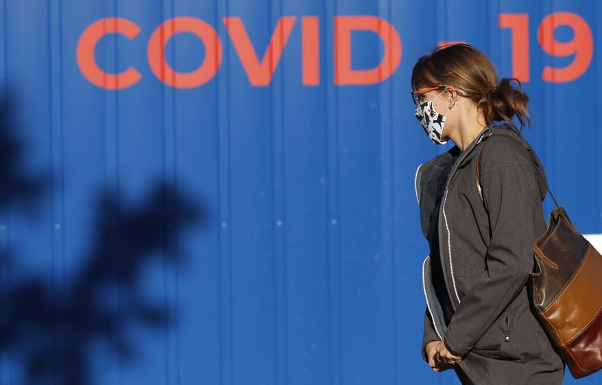 A woman wearing a face mask walks to get tested for COVID-19 at a sampling station in Prague, Czech Republic, Friday, Sept. 18, 2020. The Czech Republic has been been facing the second wave of infections. The number of new confirmed coronavirus infections has been setting new records almost on a daily basis, currently surpassing 3,000 cases in one day for the first time. (AP Photo/Petr David Josek)