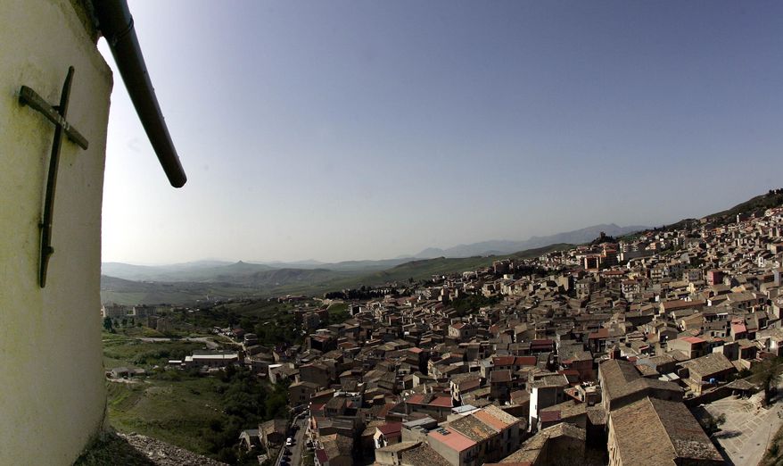 FILE -- In this file photo taken on April 24, 2006, a crucifix towers over Corleone, Italy.The Sicilian town of Corleone, made famous by the fictional Mafia clan in “The Godfather,” has ordered schools closed and a limited lockdown after a spate of coronavirus infections were tied to a big wedding there last week. (AP Photo/Gregorio Borgia)