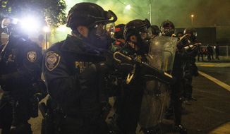 Tear gas fills the air as police take control of the streets during protests, Friday, Sept. 18, 2020, in Portland, Ore. (AP Photo/Paula Bronstein)  ** FILE **