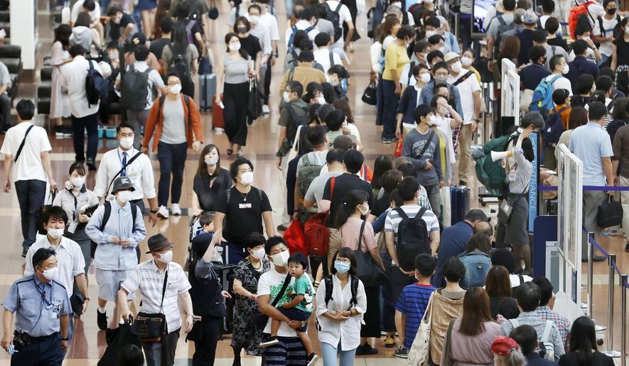 Travelers wearing face masks crowd at Haneda airport in Tokyo Saturday, Sept. 19, 2020, on the first day of the 4-day holiday. (Kyodo News via AP)