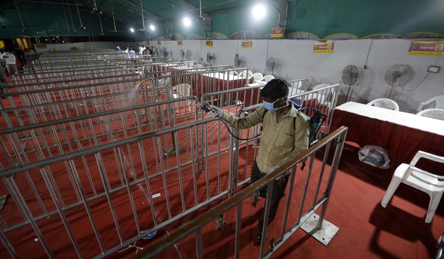 A health worker disinfects and area where tests for COVID-19 were performed, at a facility erected at a railway station to screen people coming from outside the city, in Ahmedabad, India, Friday, Sept. 18, 2020. India's coronavirus cases jumped by another 96,424 in the past 24 hours, showing little sign of leveling. India is expected to have the highest number of confirmed cases within weeks, surpassing the United States, where more than 6.67 million people have been infected. (AP Photo/Ajit Solanki)