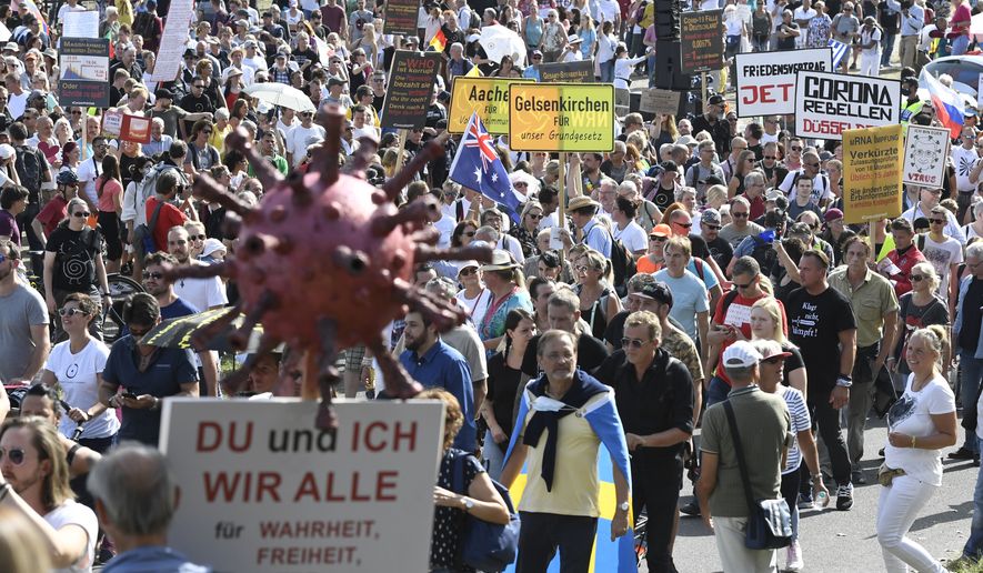 Participants of a demonstration protest with signs on the Rhine meadows against the measures to combat the coronavirus in Duesseldorf, Germany, Sunday, Sept.20, 2020. Sign reads &quot;you and m , we all for truth , freedom, love, peace.&quot;.(Roberto Pfeil/dpa via AP)