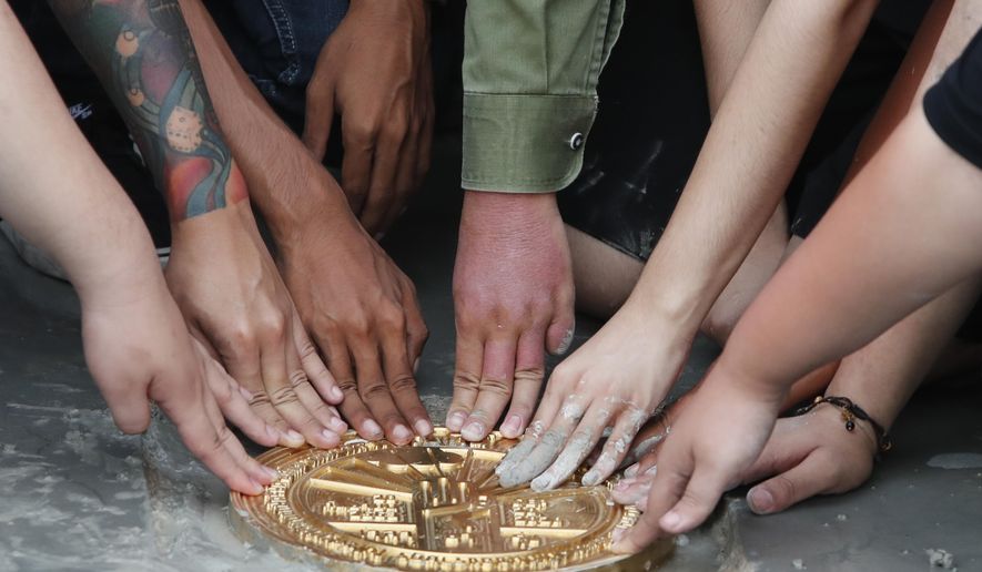 Pro-democracy student leaders install a plaque declaring "This country belongs to the people" at the Sanam Luang field during a protest in Bangkok, Thailand, Sunday, Sept. 20, 2020. Anti-government demonstrators occupying a historic field in the Thai capital on Sunday installed a plaque symbolizing the country's transition to democracy to replace the original one that was mysteriously ripped and stolen three years ago, as they vowed to press on with calls for new elections and reform of the monarchy. (AP Photo/Sakchai Lalit)