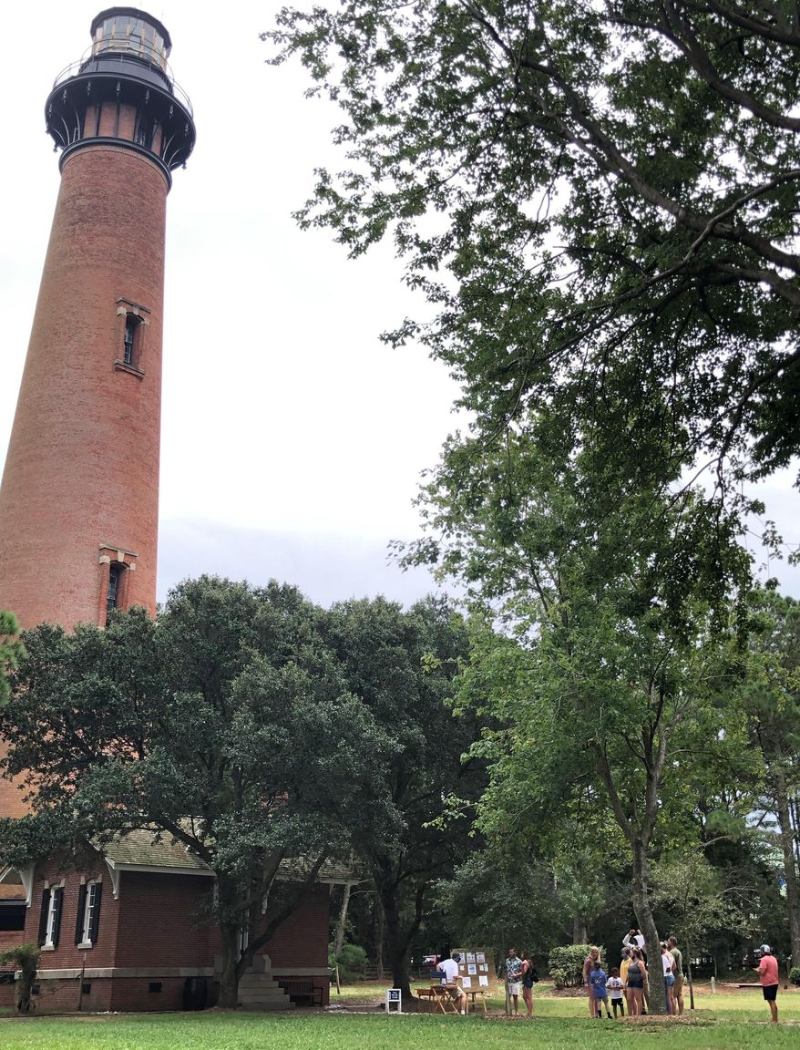 Visitors look at The Currituck Beach Lighthouse, on Wednesday, Sept. 9, 2020, in Corolla, N.C. The lighthouse reopened Monday, Sept. 7 after being closed due to coronavirus restrictions. (Jeff Hampton/The Virginian-Pilot via AP)