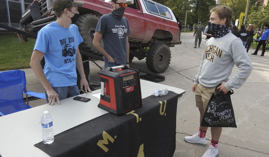 Fred Poddig, from left, and Andrew Gryspeerd, members of Four Wheelers of Michigan Tech, talk to first-year forestry student Braden Berridge during the first K-Day event of the year at Michigan Technological University in Houghton, Mich., Friday, Sept. 11, 2020. Due to COVID-19 restrictions, the university's annual K-Day event, where students get a Friday afternoon off to travel to a local beach and learn about campus activities, was held on-campus and divided into several days. (Garrett Neese/The Mining Journal via AP)