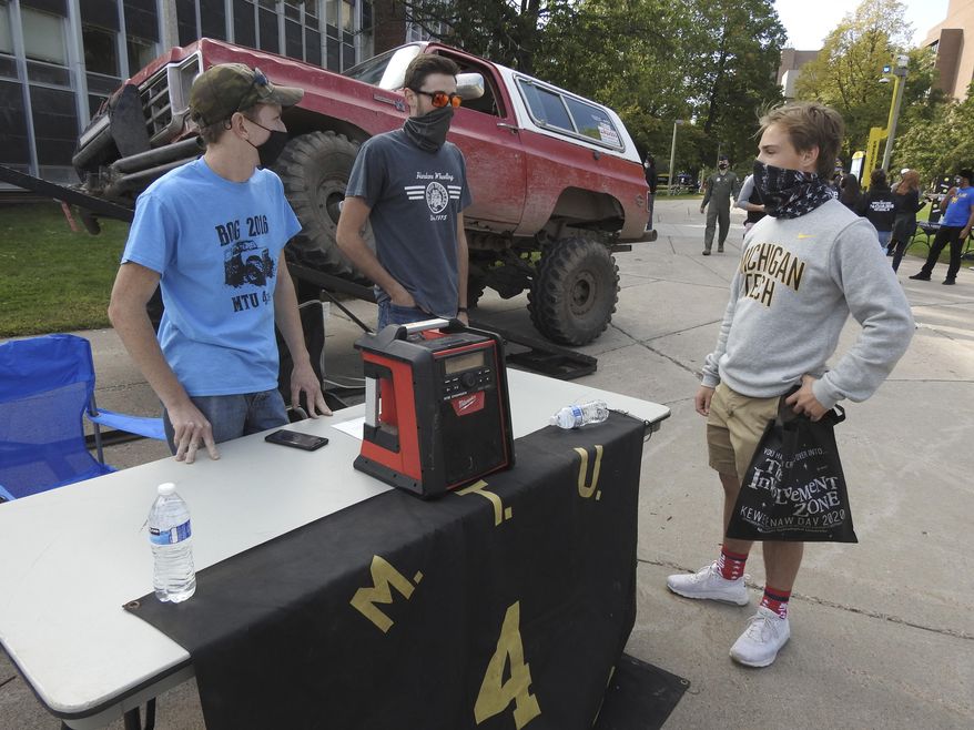 Fred Poddig, from left, and Andrew Gryspeerd, members of Four Wheelers of Michigan Tech, talk to first-year forestry student Braden Berridge during the first K-Day event of the year at Michigan Technological University in Houghton, Mich., Friday, Sept. 11, 2020. Due to COVID-19 restrictions, the university's annual K-Day event, where students get a Friday afternoon off to travel to a local beach and learn about campus activities, was held on-campus and divided into several days. (Garrett Neese/The Mining Journal via AP)