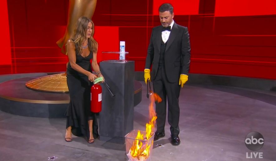 In this video grab captured on Sept. 20, 2020, courtesy of the Academy of Television Arts &amp;amp; Sciences and ABC Entertainment, Jennifer Aniston, left, and Jimmy Kimmel sanitize the winner&#39;s envelope while presenting the award for outstanding lead actress in a comedy series during the 72nd Emmy Awards broadcast. (The Television Academy and ABC Entertainment via AP)