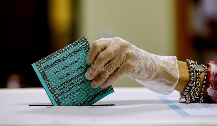 A woman casts her ballot at a polling station, in Rome, Monday, Sept. 21, 2020. On Sunday and Monday Italians are called to vote nationwide in a referendum to confirm a historical change to the country's constitution to drastically reduce the number of Members of Parliament from 945 to 600. Eighteen million of Italian citizens will also vote on Sunday and Monday to renew local governors in seven regions, along with mayors in approximately 1,000 cities. (Cecilia Fabiano/Lapresse via AP)
