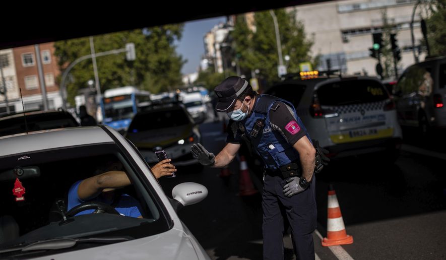 A local police stops a vehicle at a checkpoint in Madrid, Spain, Monday, Sept. 21, 2020. Police in the Spanish capital and its surrounding towns are stopping people coming in and out of working-class neighborhoods that have been partially locked down to stem Europe&#39;s fastest coronavirus spread. (AP Photo/Bernat Armangue)