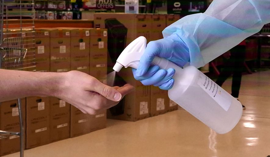 To prevent the spread of COVID-19, a customer gets a spray of hand sanitizer upon entering the Micro Center computer department store in Dallas, Monday, Sept. 21, 2020. Texas has begun allowing 75% capacity for retail and restaurant businesses in most of the state except a few counties on the U.S.-Mexico border. (AP Photo/LM Otero)