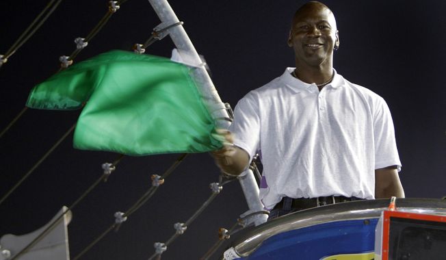 FILE - In this May 22, 2010, file photo, Charlotte Bobcats owner Michael Jordan practices waving the green flag before a NASCAR All-Star auto race at Charlotte Motor Speedway in Concord, N.C. Denny Hamlin is starting his own race car team in partnership Jordan and Bubba Wallace as the driver. (AP Photo/Chuck Burton, File)