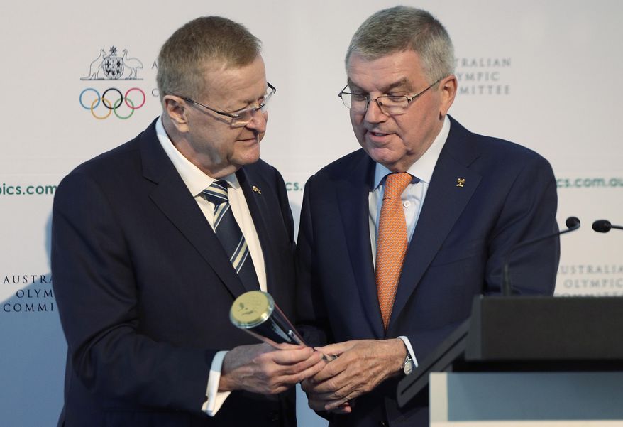 FILE - In this May 4, 2019, file photo, International Olympic Committee President Thomas Bach, right, is presented with the Australian Olympic Committee (AOC) President&#39;s trophy by AOC president John Coates at the AOC annual general meeting in Sydney, Australia. The only thing more difficult than staging next year&#39;s Tokyo Olympics in a pandemic might be convincing sponsors to keep their billions on board in the midst of economic turbulence and skepticism. (AP Photo/Rick Rycroft, File)