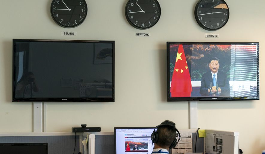 A reporter with the Xinhua Press Agency watches as President Xi Jinping is seen on a video screen remotely addressing the 75th session of the United Nations General Assembly, Tuesday, Sept. 22, 2020, at U.N. headquarters. This year's annual gathering of world leaders at U.N. headquarters will be almost entirely "virtual." Leaders have been asked to pre-record their speeches, which will be shown in the General Assembly chamber, where each of the 193 U.N. member nations are allowed to have one diplomat present. (AP Photo/Mary Altaffer)